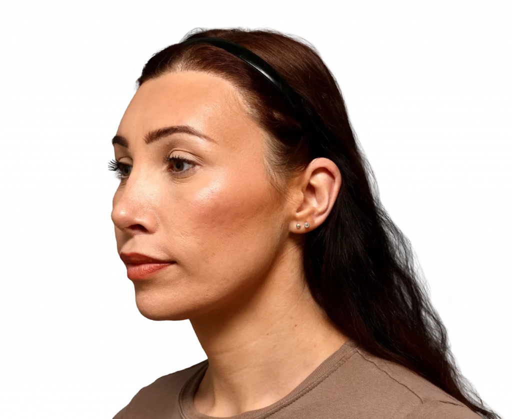 Side profile of a woman with brown hair wearing a black headband, neutral makeup, and small stud earrings, facing left.