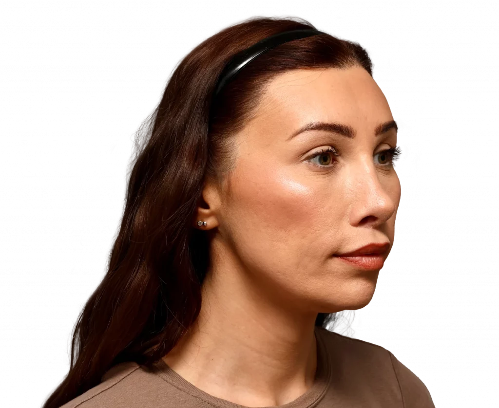 Side profile of a woman with brown hair, wearing a black headband and small stud earrings, neutral expression.
