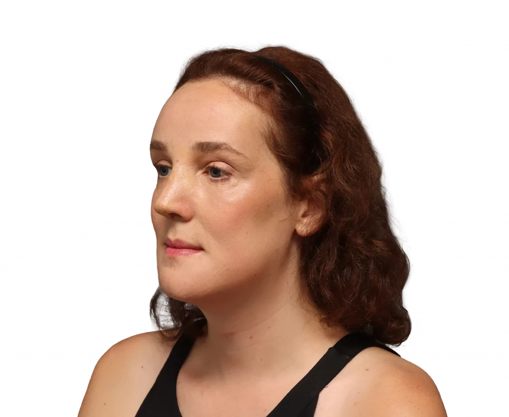 Side profile of a woman with brown curly hair wearing a black sleeveless top, facing left with neutral expression.