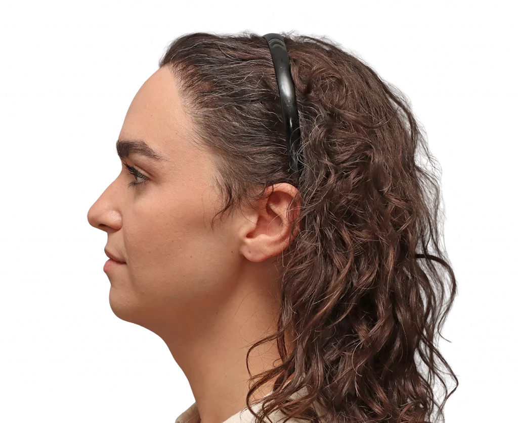 Side profile of a woman with brown wavy hair wearing a black headband