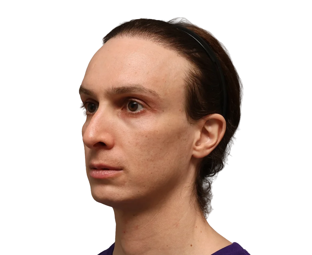 Side profile of a woman with brown hair pulled back by a black headband, wearing a purple top against a black background.