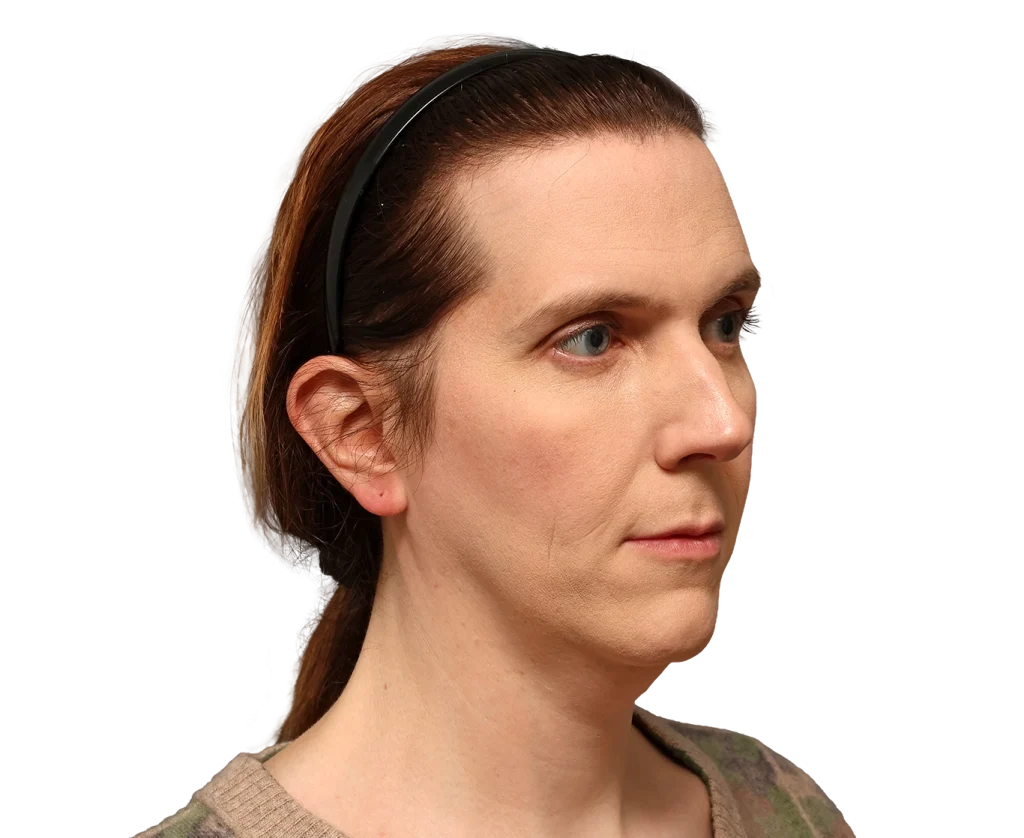 Side profile of a woman with light skin and brown hair tied back, wearing a black headband.